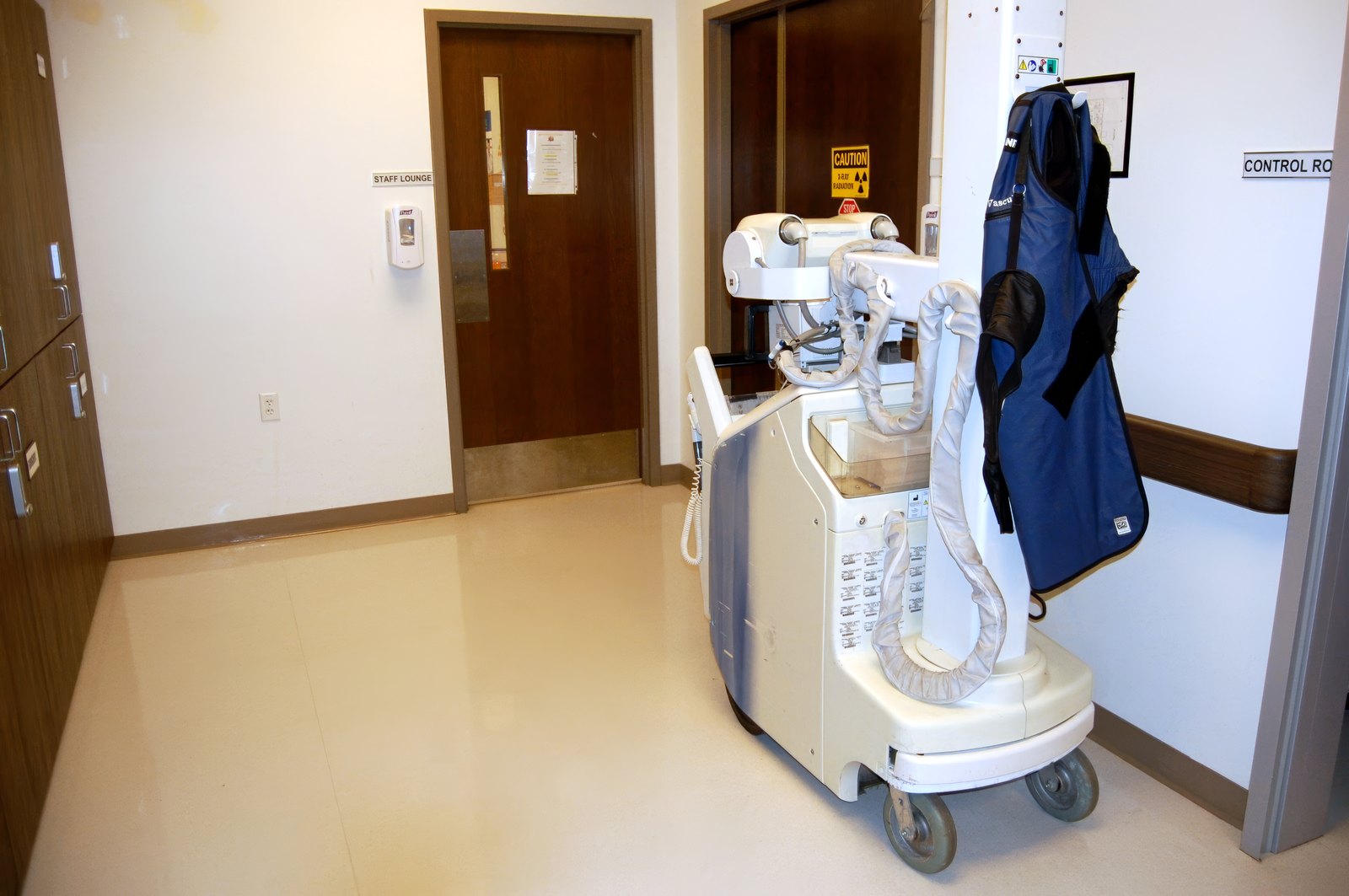 A portable X-ray unit standing in a corridor at El Mirage ER, with a lead apron hanging on its hook.