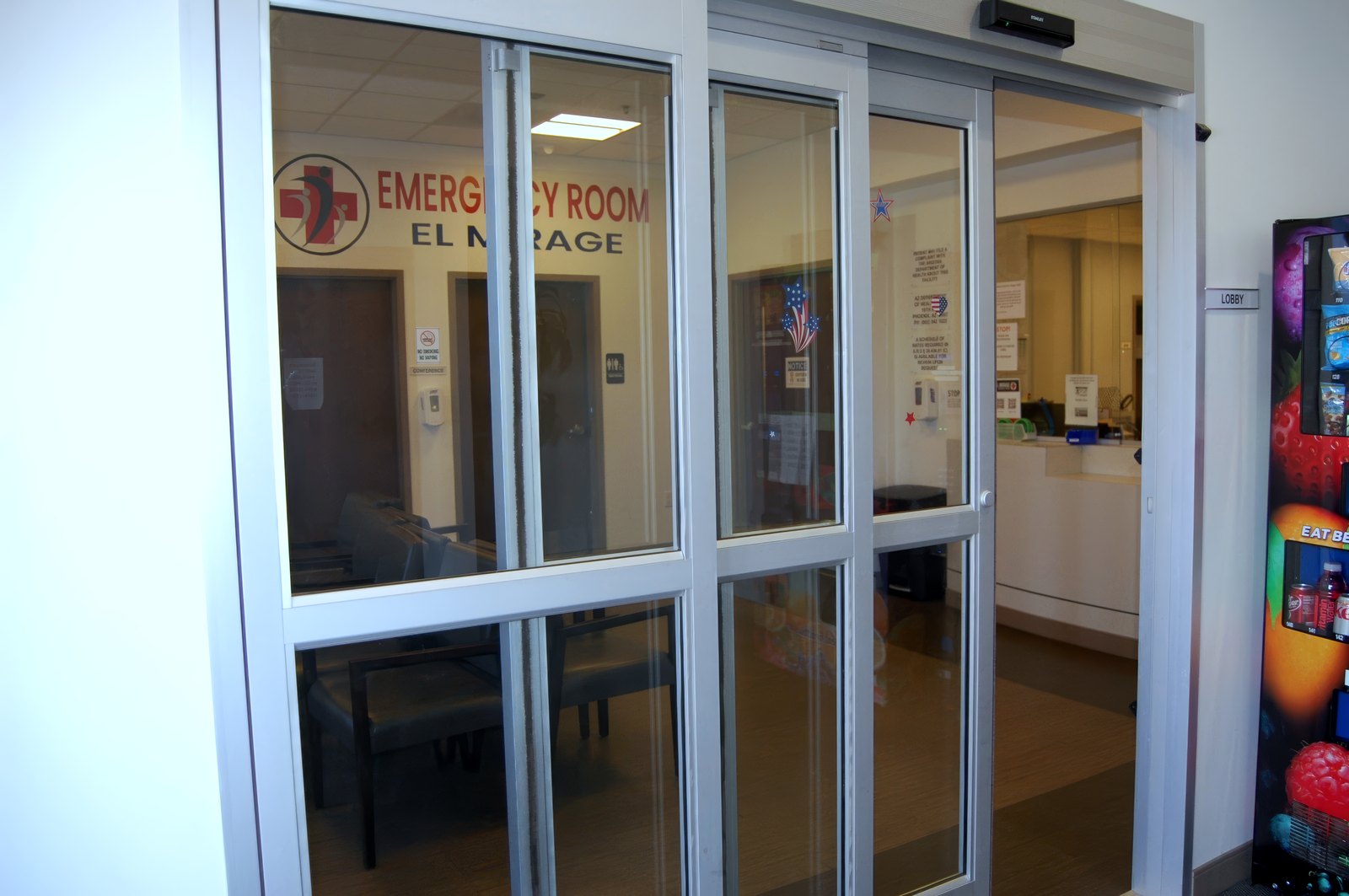 The automatic entrance doors at El Mirage ER, with the emergency room emblem on the glass.