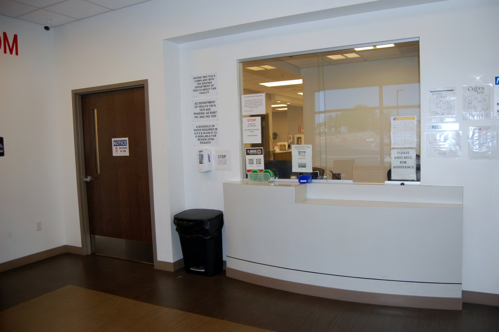 The reception and triage window at El Mirage ER, with a white counter and a glass screen.